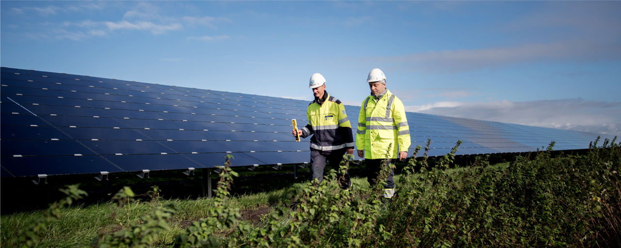 Deux hommes marchant à côté de deux panneaux solaires